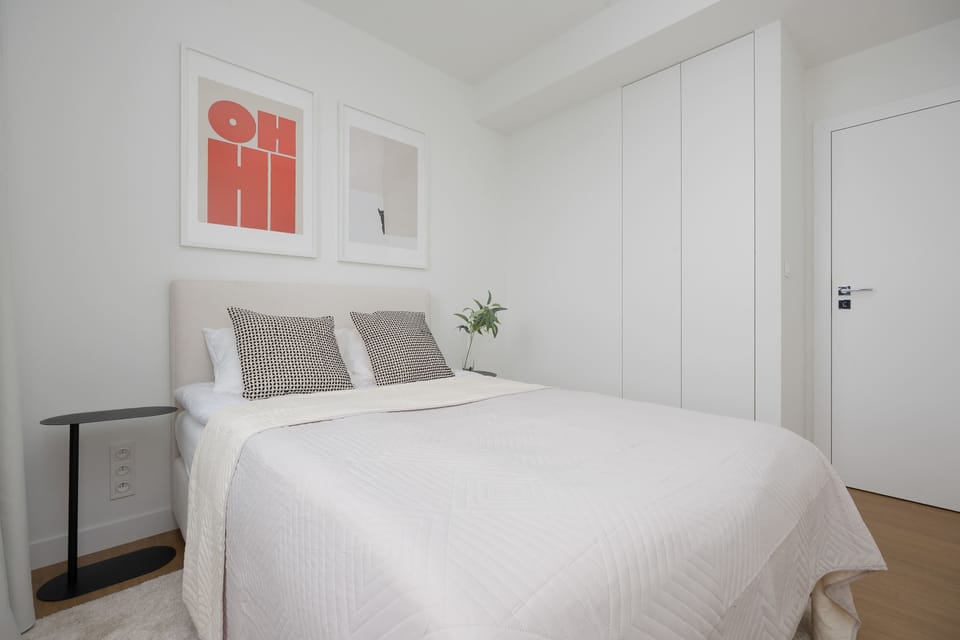 Bright bedroom with large windows, neutral décor, and a calm contemporary ambiance.