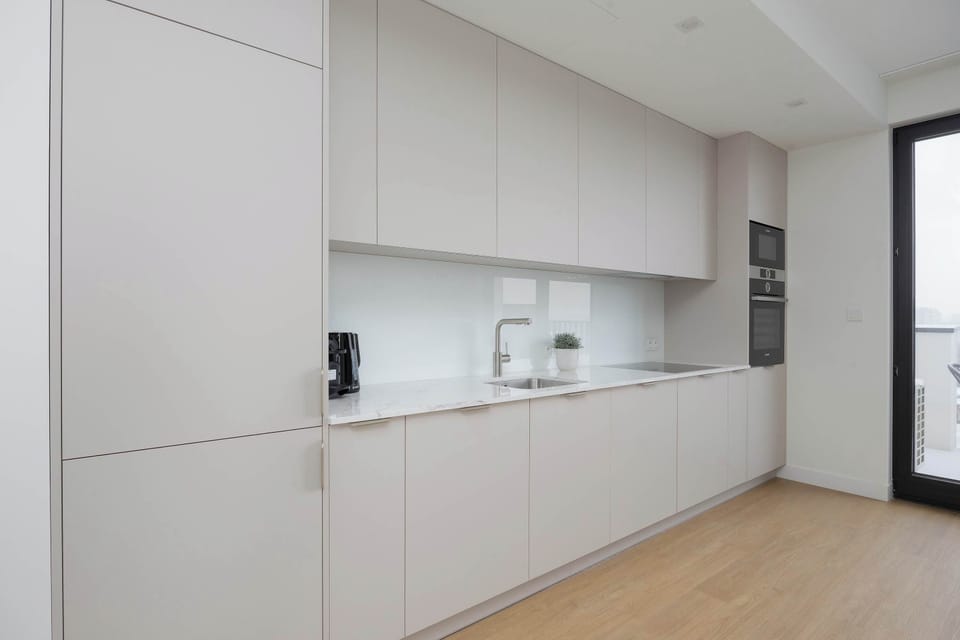 Sleek open-plan kitchen with clean white cabinetry, integrated appliances, and a spacious, uncluttered layout.