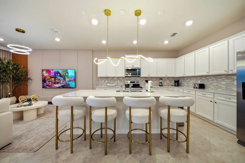 Welcome to this bright kitchen, featuring sleek white cabinetry and beautiful backsplash tiles for a modern touch. The inviting island with plush bar stools and stylish pendant lighting is ideal for meals and conversation.