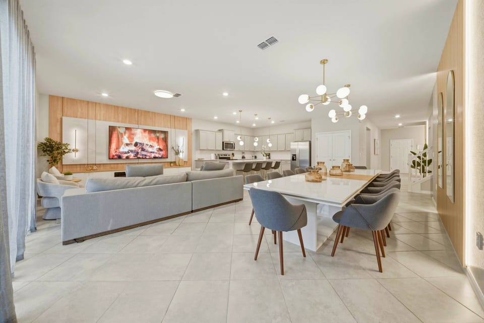Step into a spacious living area where soft gray sofas invite relaxation, and a striking chandelier adds a touch of charm. The elegant dining table, surrounded by modern chairs, sets the stage for memorable meals with loved ones.