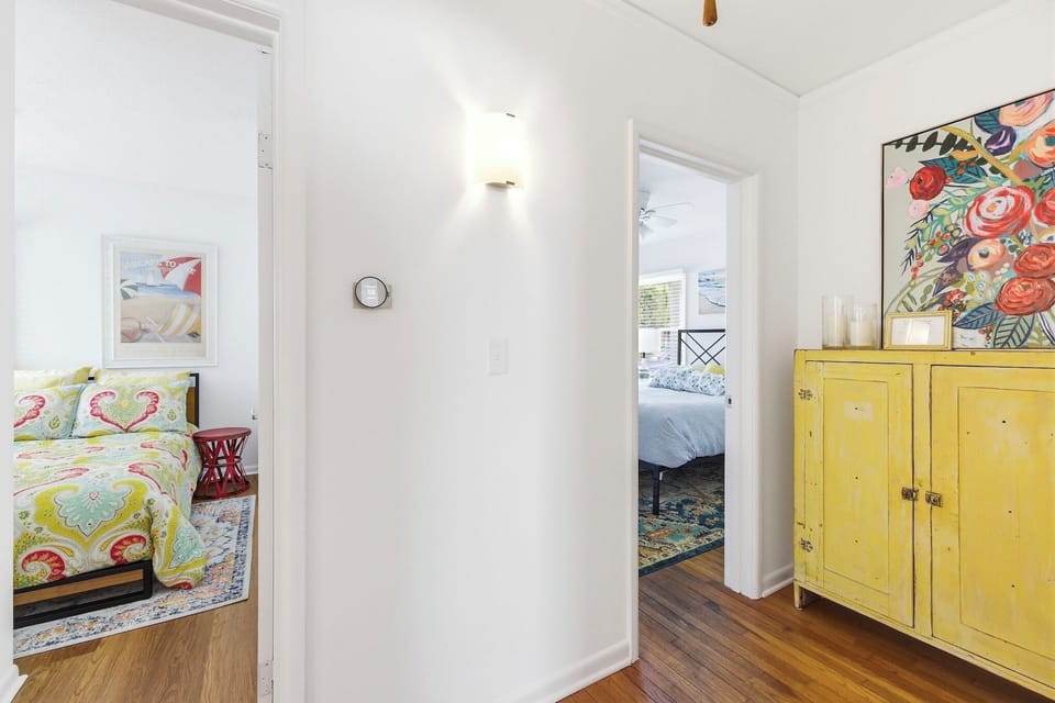 Bright hallway connecting bedrooms, featuring hardwood floors and cheerful coastal accents.