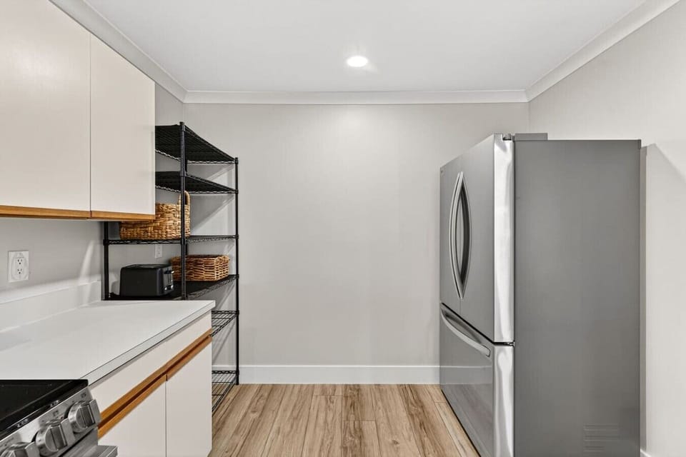 Spacious kitchen pantry area with stainless steel refrigerator and extra shelving for extended beach stays.