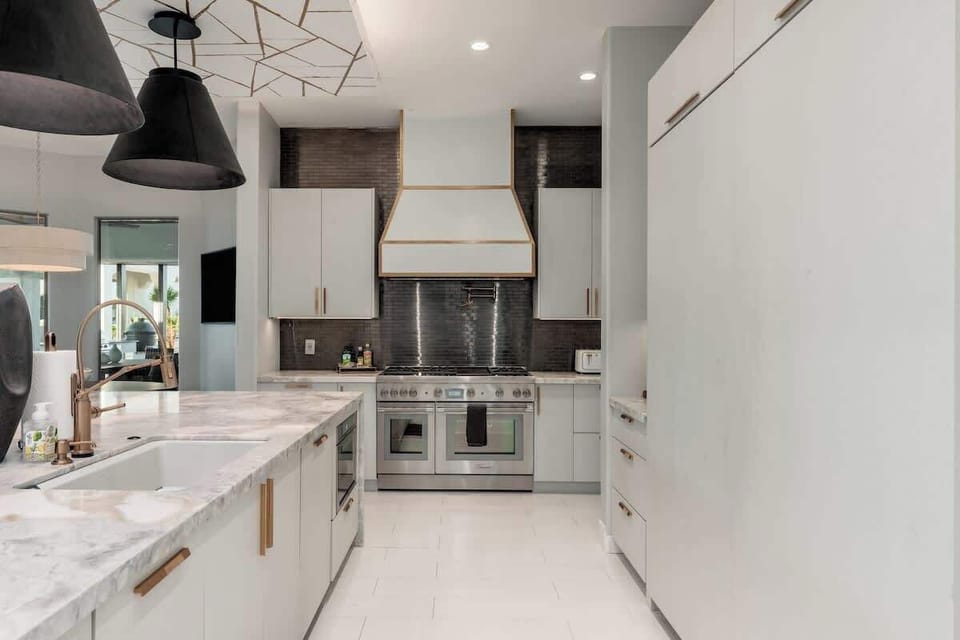 Your gourmet kitchen awaits with sleek white cabinetry, marble counters, and professional-grade appliances—perfect for preparing memorable meals during your stay.