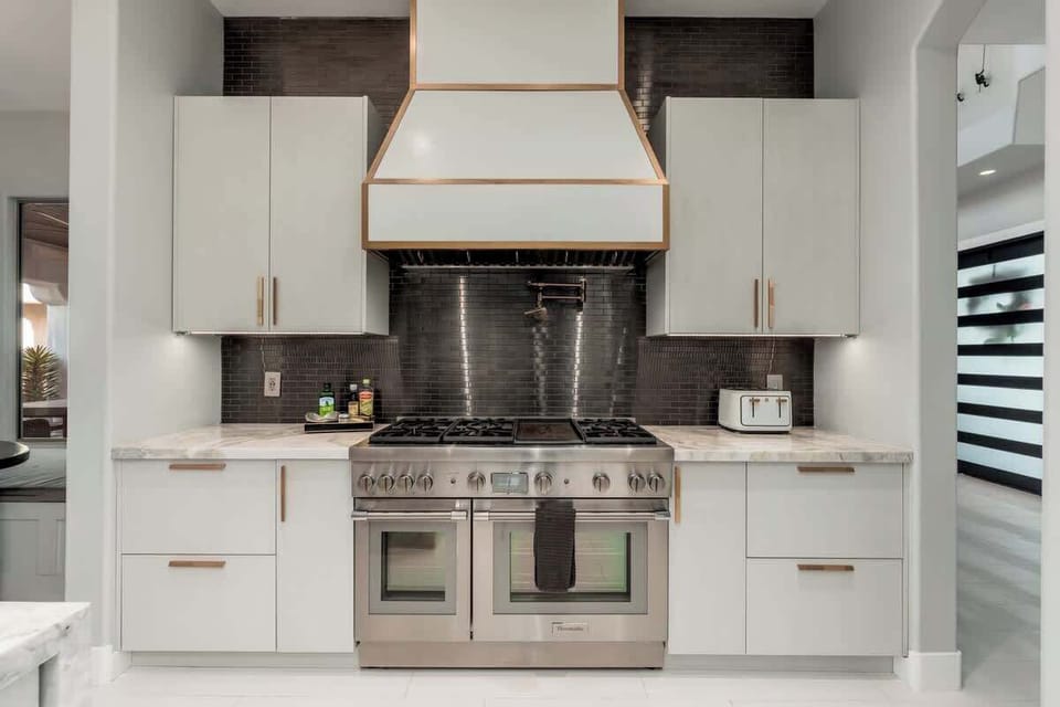 Cook your favorite meals on a sleek range while enjoying crisp subway tile and elegant marble countertops in this beautifully designed kitchen space.