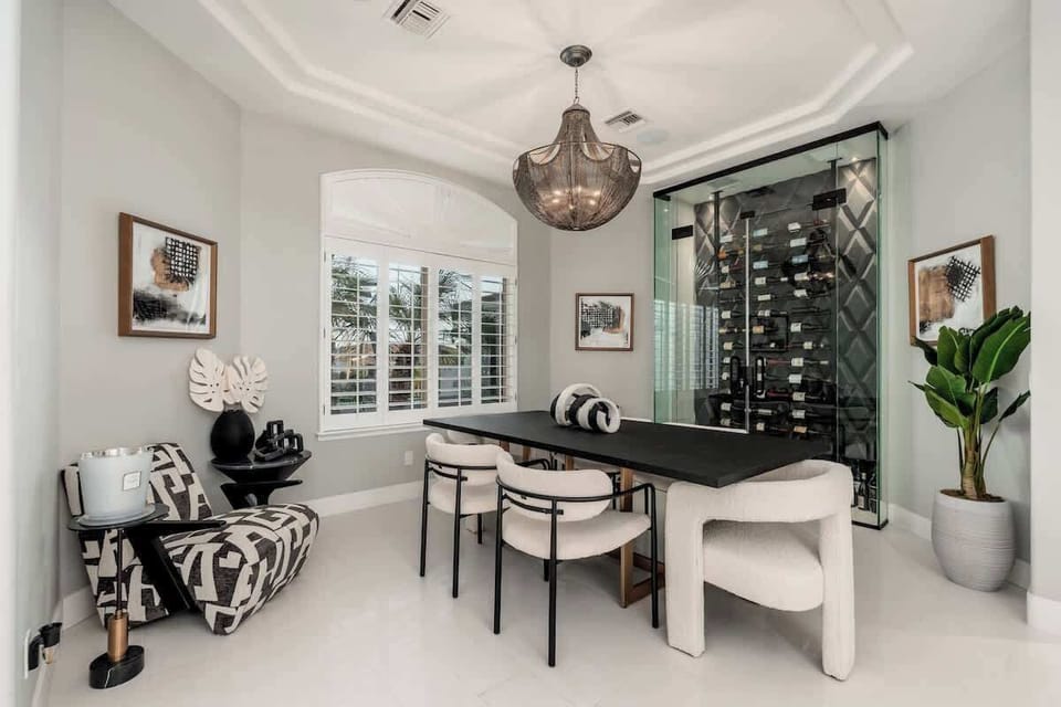 Your elegant dining space features a statement chandelier, modern seating, and a stylish glass-enclosed wine display—perfect for memorable meals and gatherings.