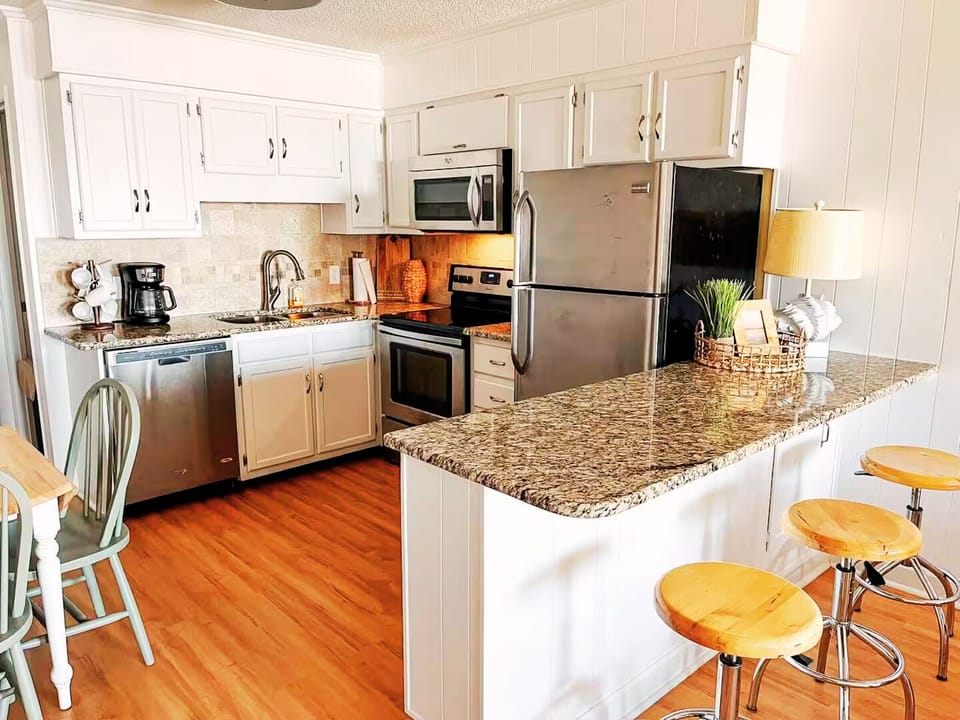 Bright modern kitchen with granite counters, stainless appliances, and bar seating