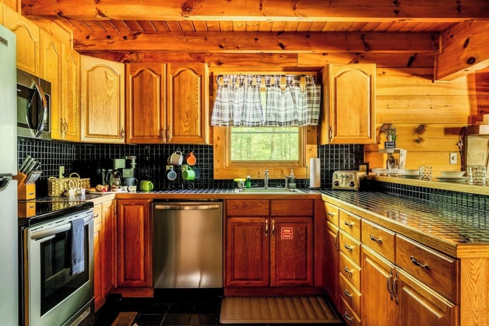 Well-stocked kitchen with wood cabinets, dishwasher, stove, microwave, and country charm — everything you need to cook a home-cooked meal