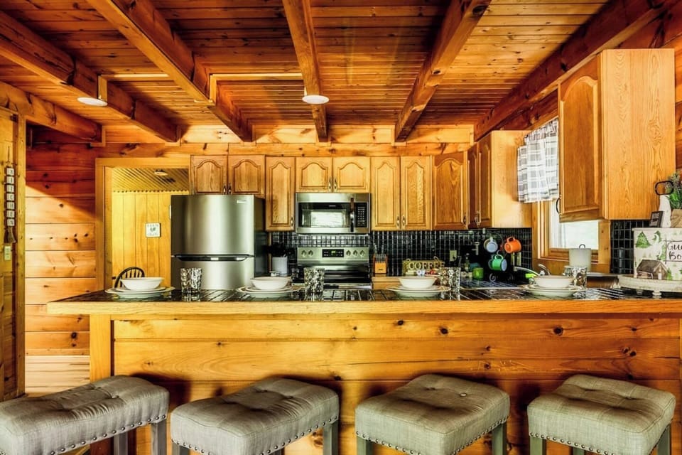 Fully equipped kitchen with breakfast bar, bar stools, stainless steel appliances, and ample counter space for cooking large group meals