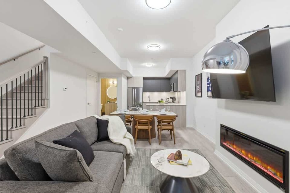Bright living room with Smart TV, fireplace, and cozy seating by large windows