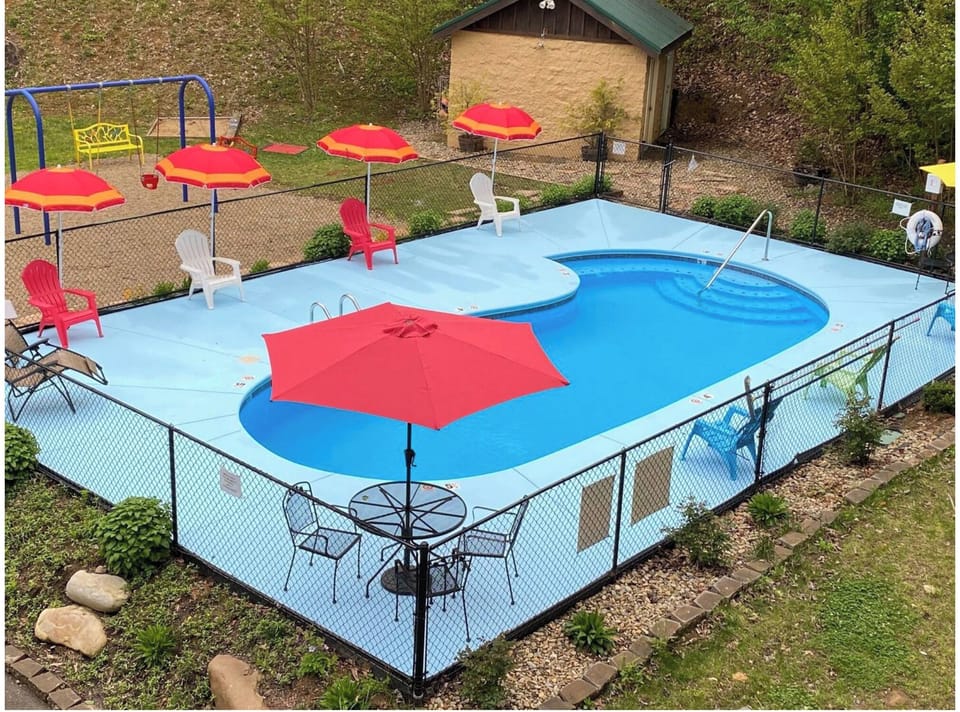 Public fenced pool with shaded seating and a family-friendly outdoor setup