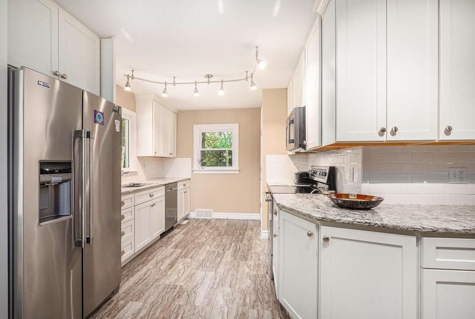 Modern kitchen with white cabinetry, granite countertops and stainless steel appliances.