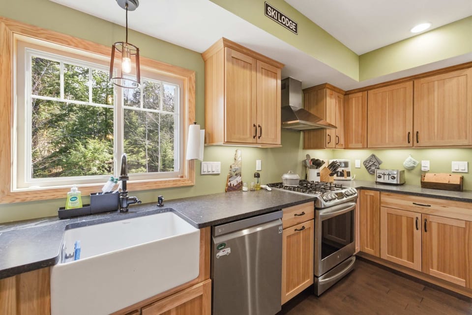 The farmhouse apron sink, gas range, and pro-grade hood — the working core of a kitchen that can handle a group of 11.
