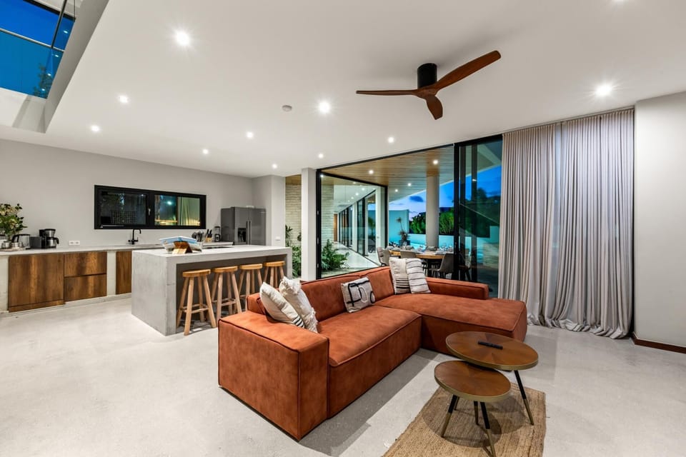 Bright, open concept living area with a fully equipped kitchen, comfortable seating and wide sliding doors opening directly to the pool terrace.