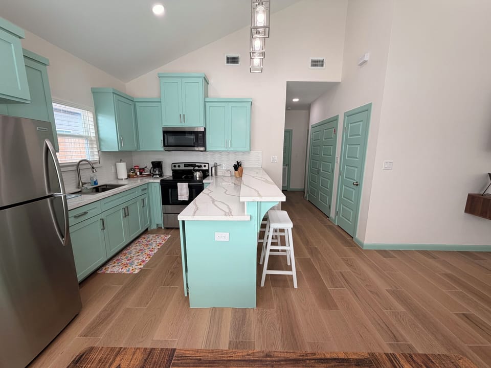 Bright modern kitchen with mint cabinets, island seating, and vaulted ceilings