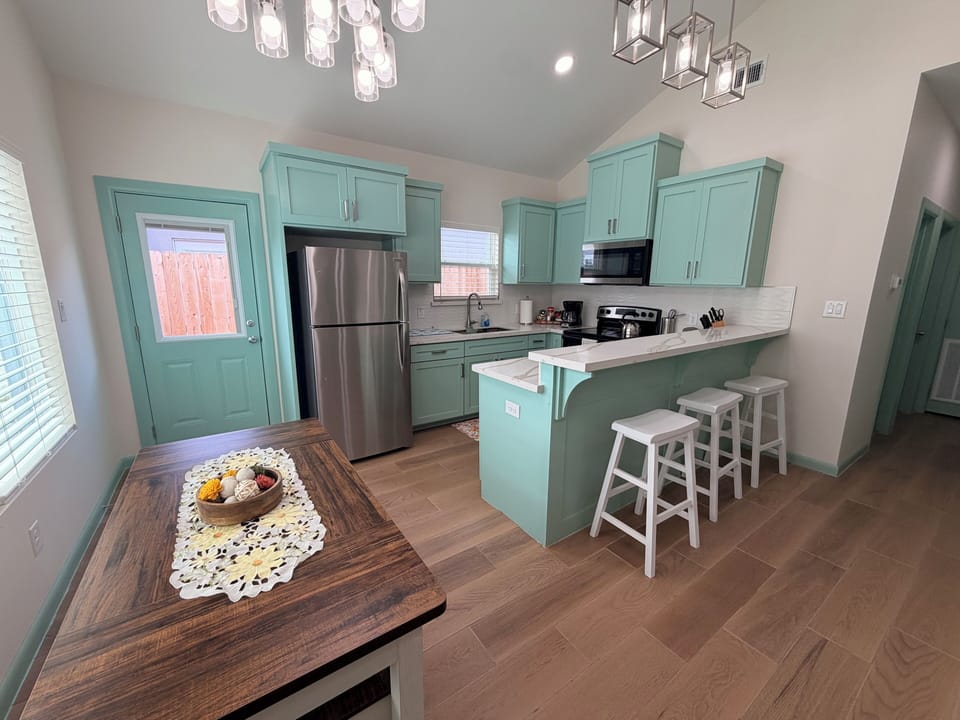 Bright mint kitchen with breakfast bar, modern lighting, and stainless appliances
