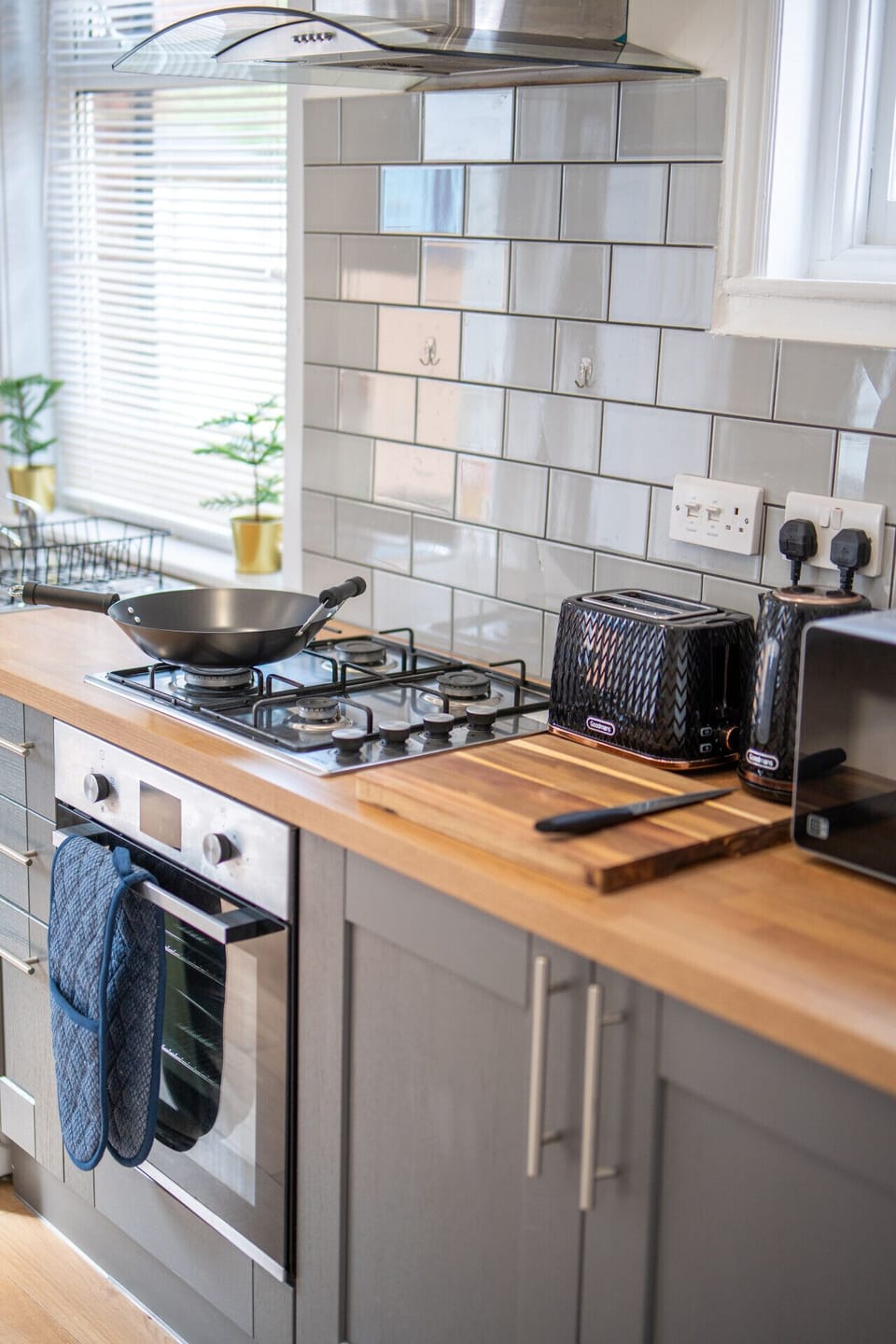 Cooktop and oven area with extractor hood, wok, chopping board, toaster, kettle, and microwave.