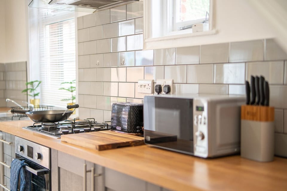 Kitchen counter with microwave, knife block, chopping board, toaster, hob, and a wok.