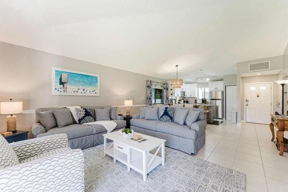 Bright and spacious coastal-inspired living room with oversized seating, Smart TV, cable, and direct access to the patio and outdoor dining area.
