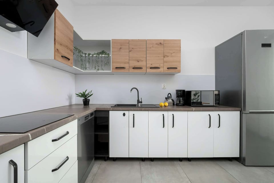 A modern kitchen with white cabinets and wooden details. It is fully equipped and functional for daily use.