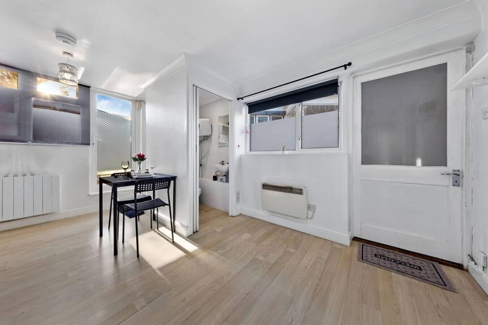 Bright dining area with a table and chairs, a door with frosted glass, and an open doorway to the bathroom.