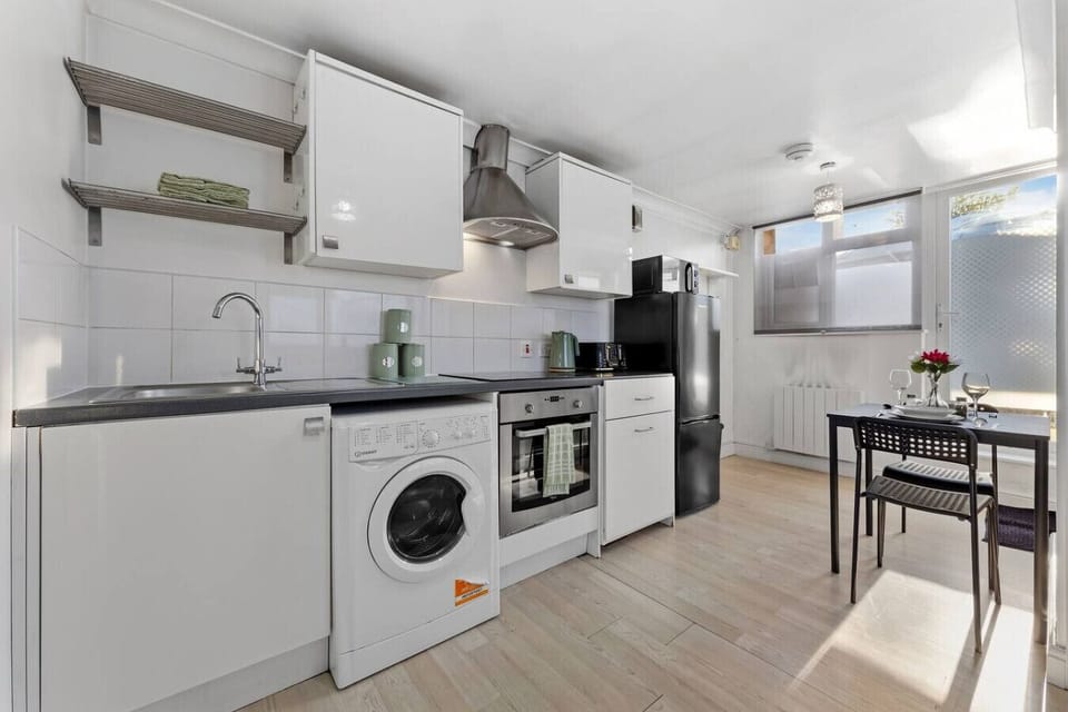 Kitchen and dining area with sink, hob and oven, washing machine, fridge, and a dining table set for two.