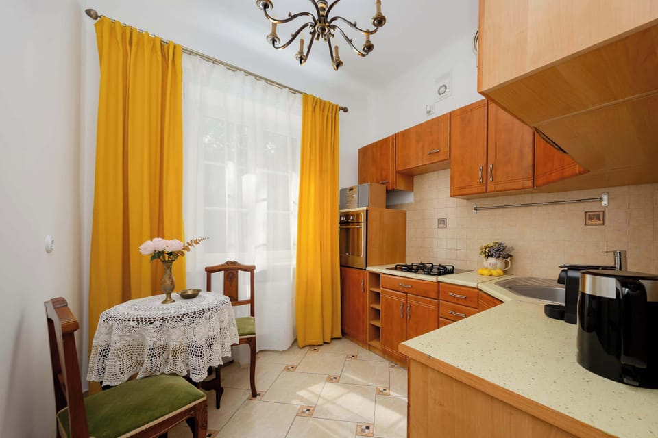 A traditional kitchen with wooden cabinets, tiled backsplash, and a small dining area near the window.