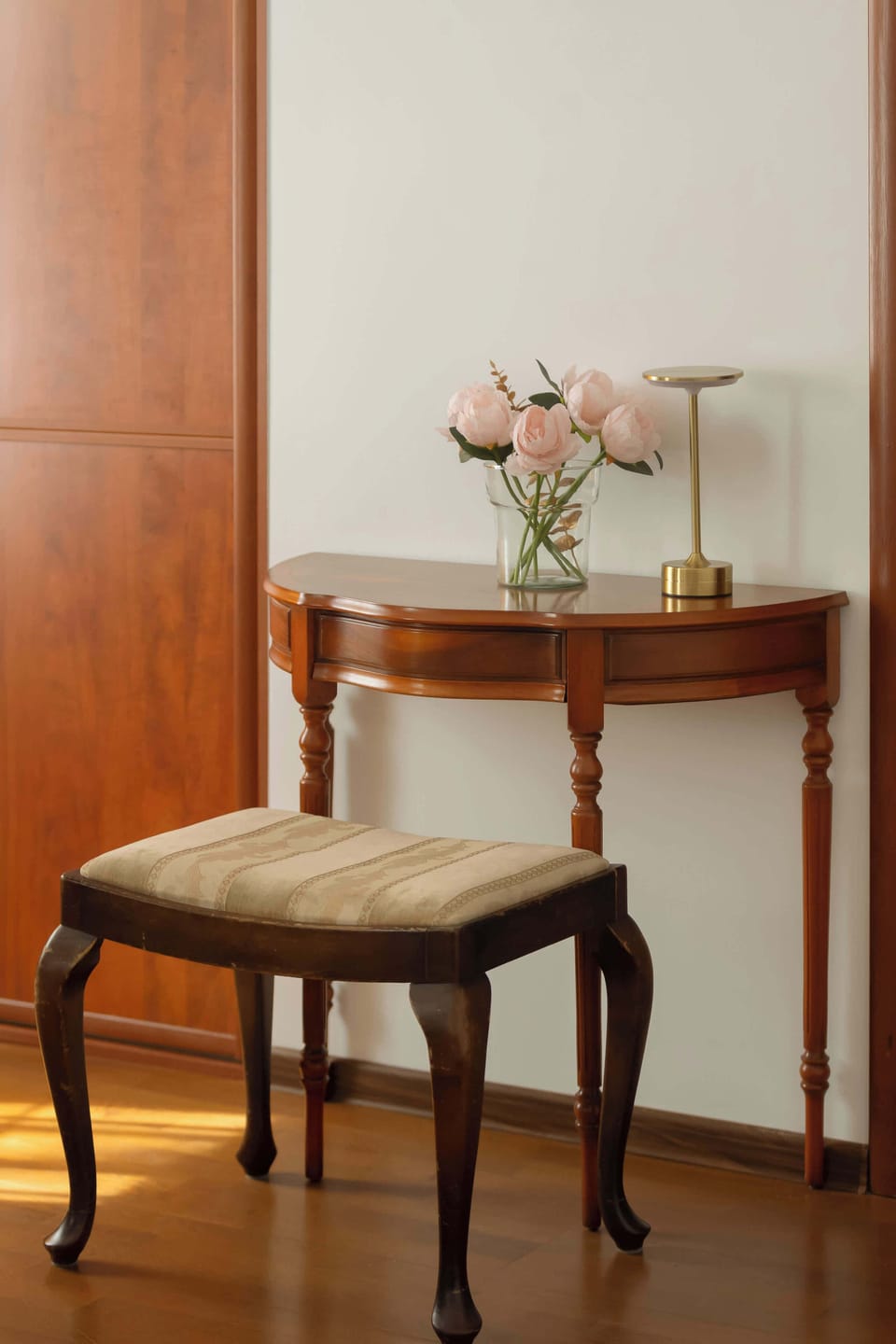A small table with a chair placed near a wall, decorated with a vase and flowers.