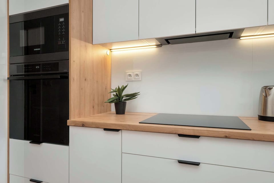 A close-up of a sleek kitchen wall with built-in appliances and clean cabinetry.