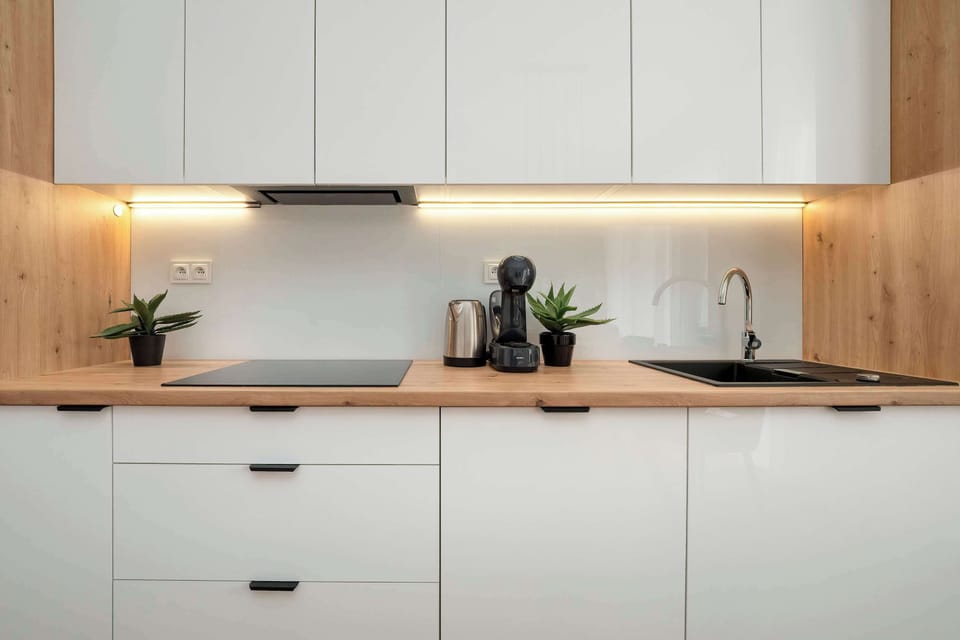  A bright kitchen corner with glossy cabinets, wooden accents, and subtle decorative elements.