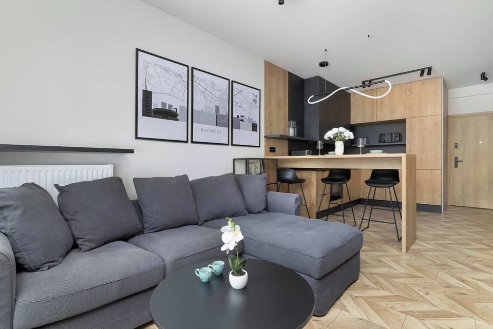 A cozy lounge area with a gray sofa, coffee table, and open kitchen in the background.