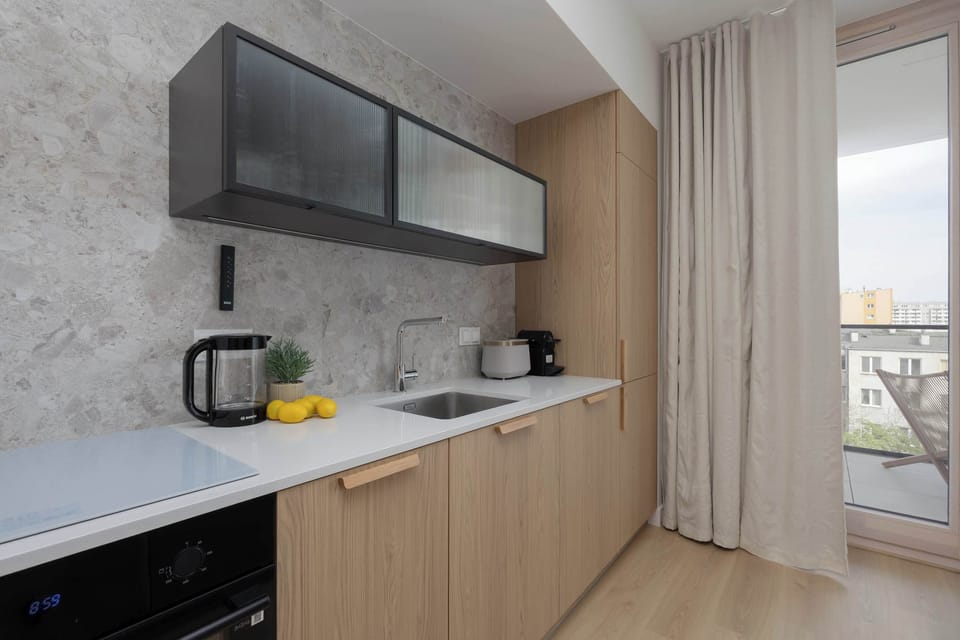 A kitchenette with upper cabinets, a stove, and a light stone backsplash.