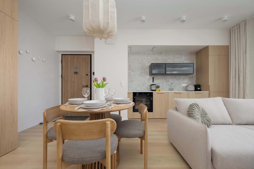 An open-plan living space with a dining table, sofa, and bright natural lighting.
