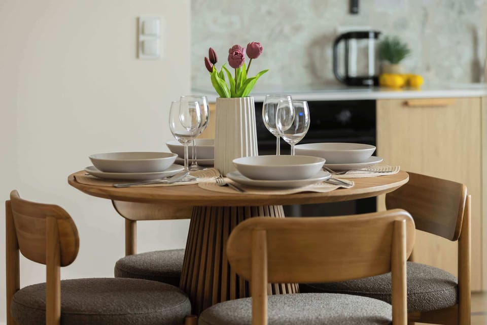 A small dining table set with plates, glasses, and decorative flowers.