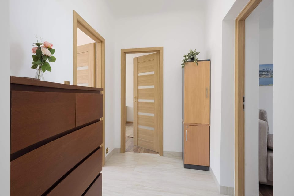 A hallway interior with wooden furniture, white walls, and open doors leading to other rooms.