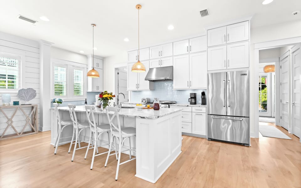 Gather around this bright kitchen island where crisp white cabinetry meets warm wood floors. Stainless appliances and gleaming countertops make meal prep a breeze.