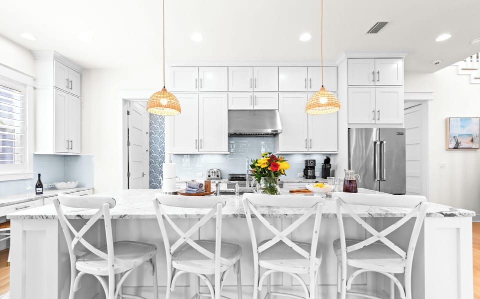 Your bright kitchen with island seating for six, modern appliances, and warm coastal lighting invites easy mornings and relaxed gatherings.
