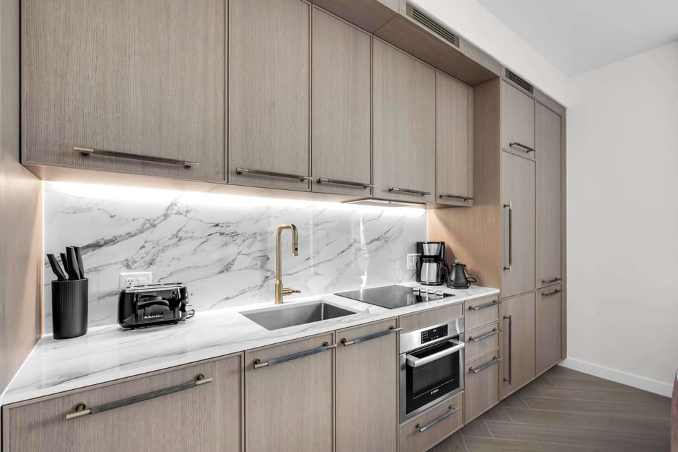 Cook like a pro in this sleek kitchenette! Marble backsplash, modern wood cabinetry, and full appliances—coffee maker, toaster, cooktop, and oven—make meal prep a breeze during your Miami stay.