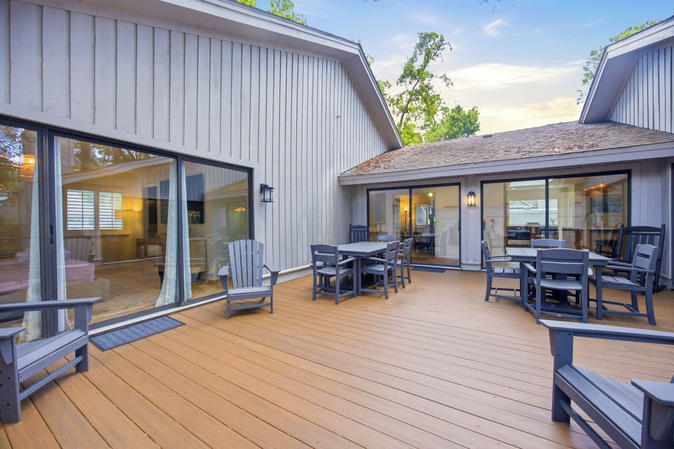 Cedar planks glow under an open sky on this spacious deck, where slate blue seating invites long conversations. Sliding glass doors bridge the gap between the airy interior and the calm of the outdoors.