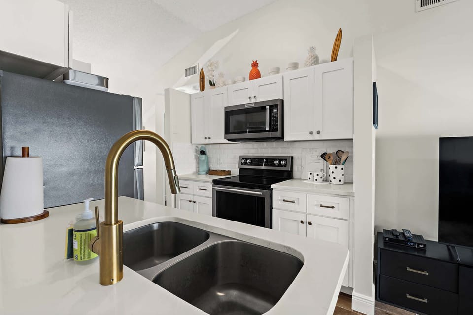 Updated Kitchen with Gold Faucet and White Tile Backsplash
