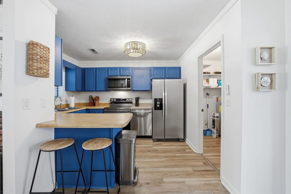  Modern Kitchen w/ Stainless Steel Refrigerator, Built-In Microwave, Stove, Dishwasher, Cooking Utensils, and Island Seating