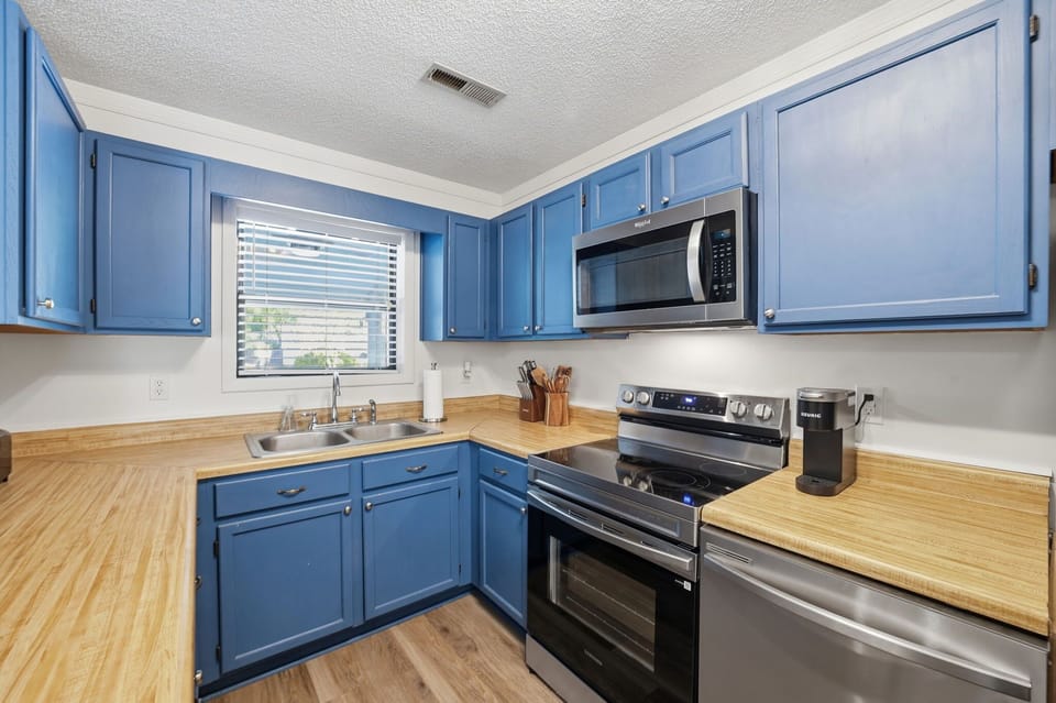  Modern Kitchen w/ Stainless Steel Refrigerator, Built-In Microwave, Stove, Dishwasher, Cooking Utensils, and Island Seating