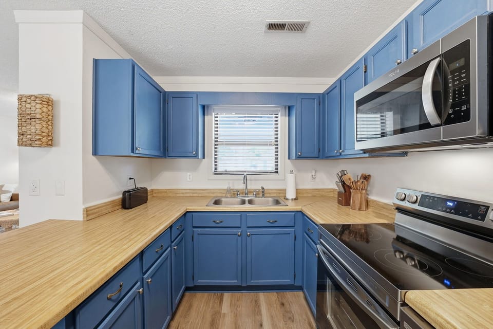  Modern Kitchen w/ Stainless Steel Refrigerator, Built-In Microwave, Stove, Dishwasher, Cooking Utensils, and Island Seating