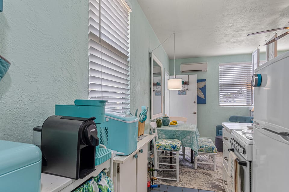 A compact kitchen area with pastel turquoise appliances and a small dining table topped with patterned cloth.