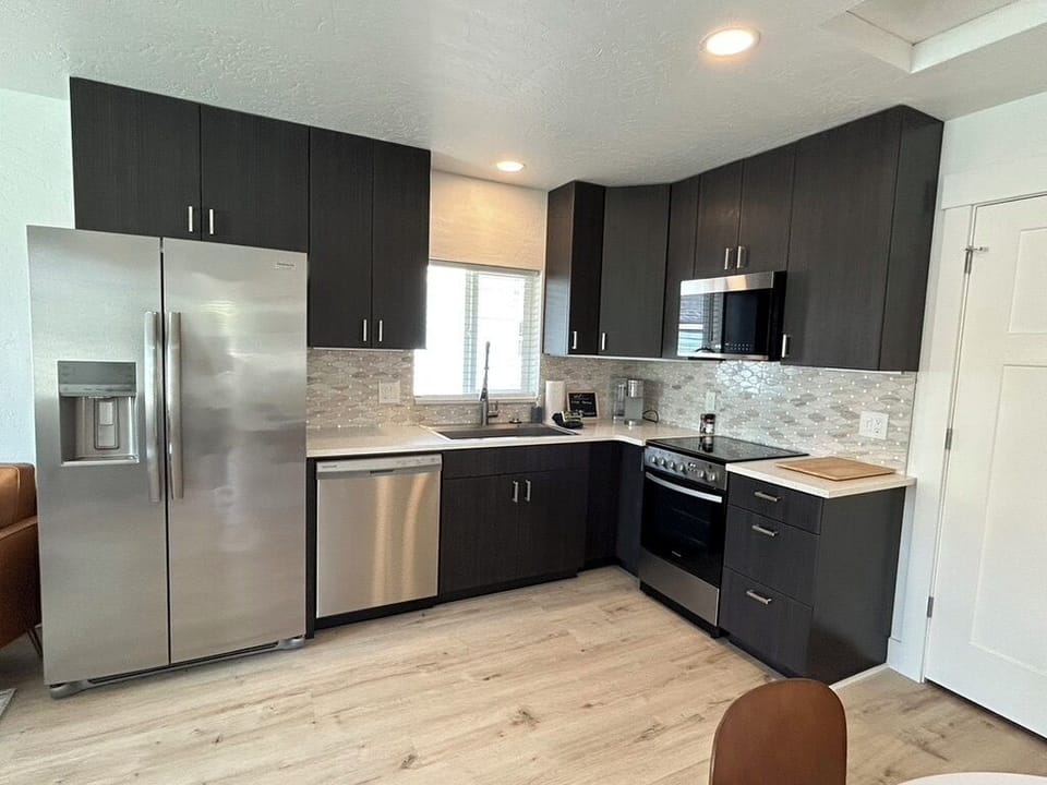 Your modern kitchen features sleek dark cabinetry, stainless steel appliances, and elegant tile backsplash—everything you need to whip up delicious meals during your stay.