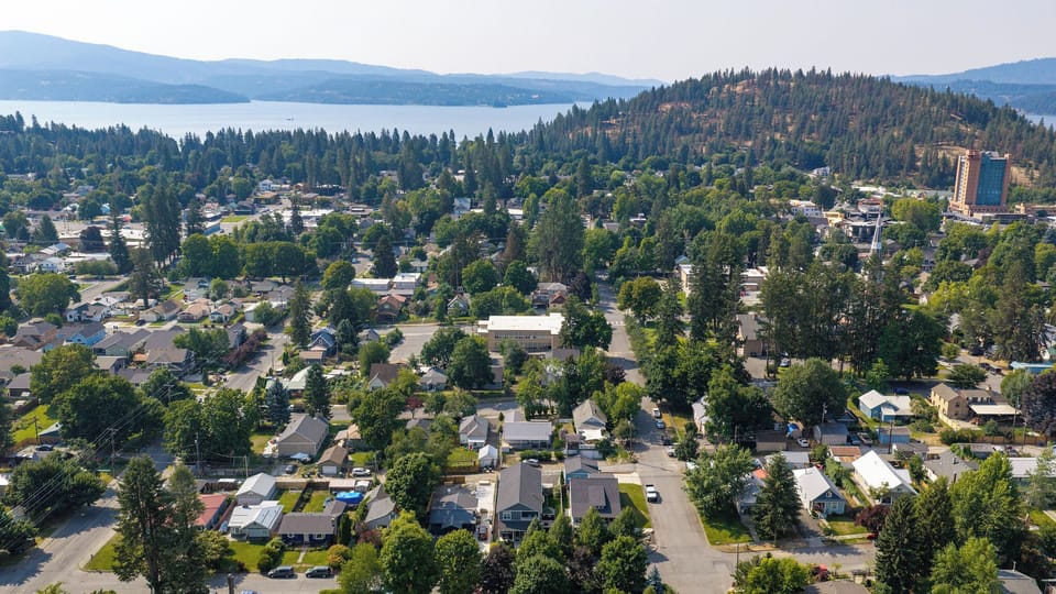 A serene residential neighborhood nestled among evergreen forests, with tranquil lake and mountain vistas creating a peaceful natural setting.