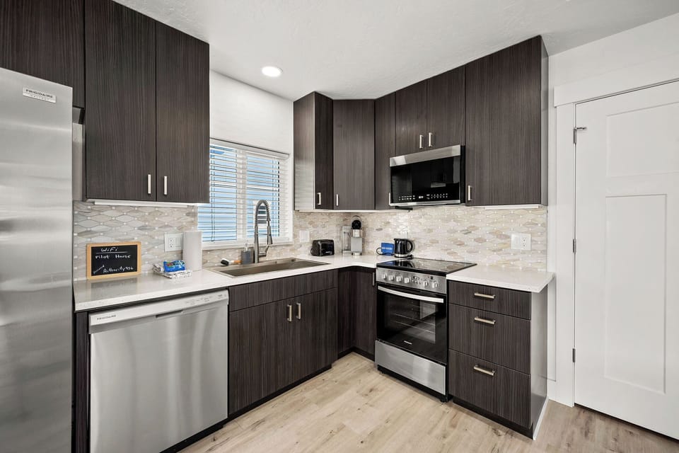 Step into your fully equipped kitchen where sleek dark cabinetry meets modern stainless appliances. Whip up your favorite meals with everything you need right at your fingertips.
