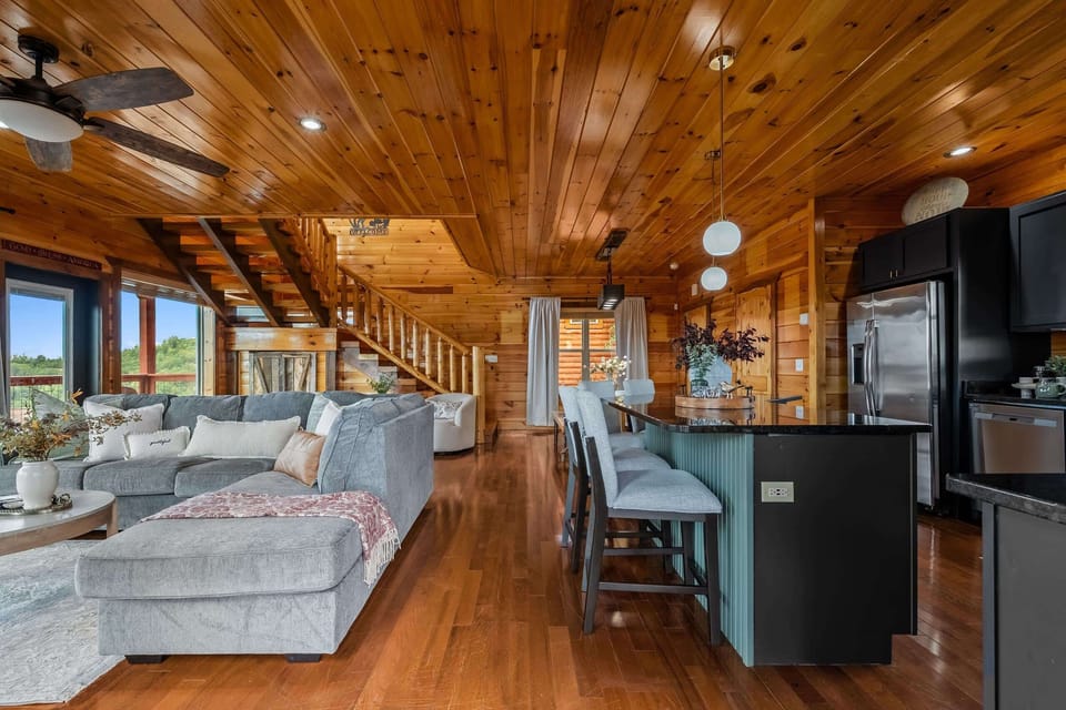 Step inside to a soaring great room: vaulted timber ceilings, a deep sectional, and walls of glass framing the mountains.