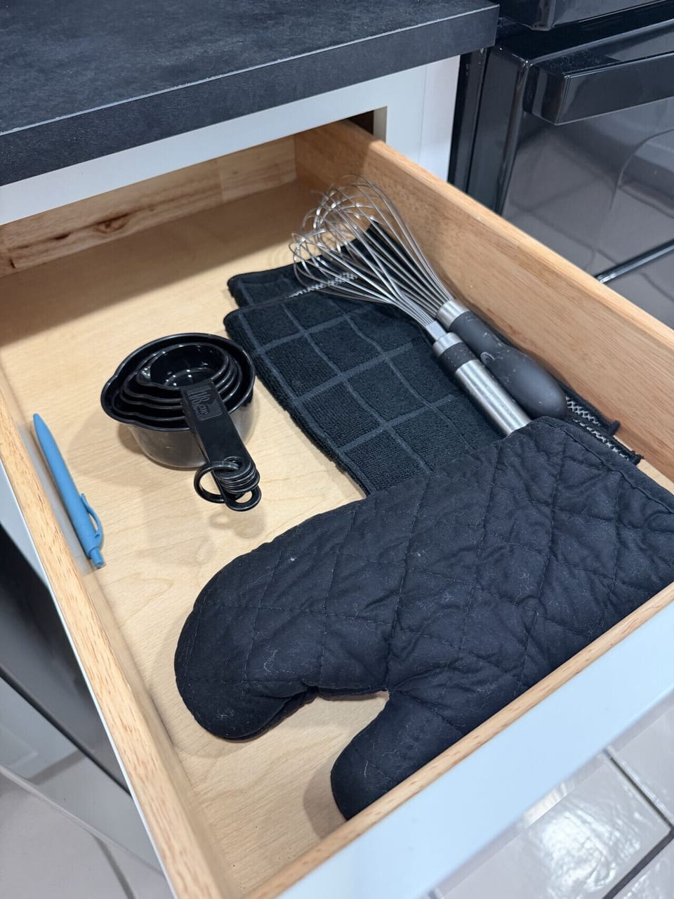 Drawer with measuring cups, whisk, oven mitts, and prep tools