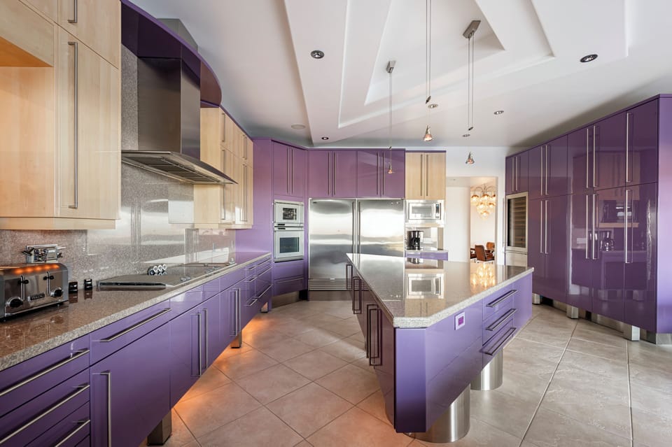Blending bold design with exceptional functionality, the gourmet kitchen features custom lacquer cabinetry, oversized waterfall-style workspaces, and top-tier appliances in a truly one-of-a-kind contemporary setting.