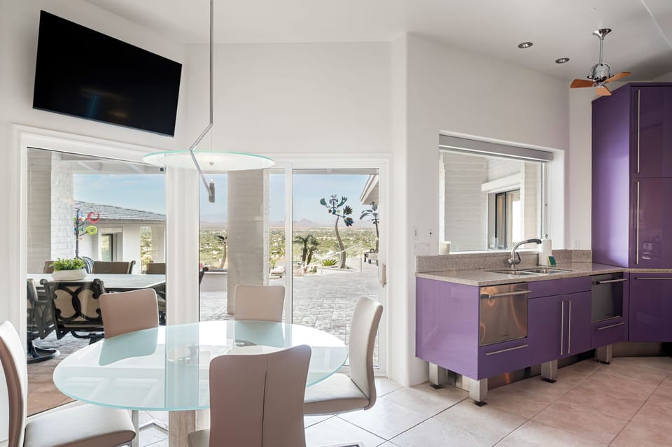 Bathed in natural light, the dining area and adjacent prep kitchen offer a sleek, modern atmosphere with seamless access to outdoor entertaining spaces and stunning panoramic views beyond.